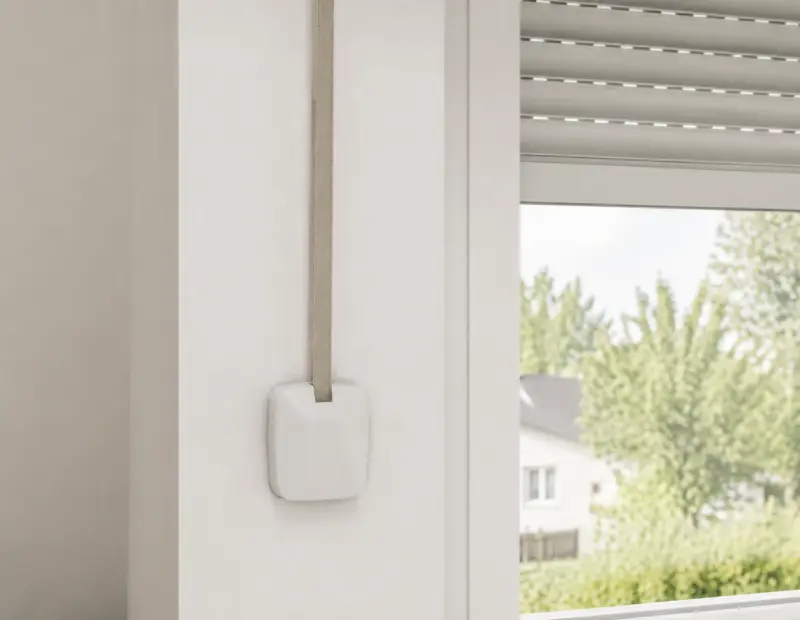Manueller Gurtwickler neben einem Fenster mit Rollladen